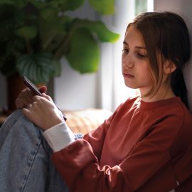 Teenager sidder alene med mobil