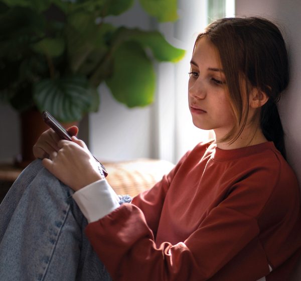 Teenager sidder alene med mobil